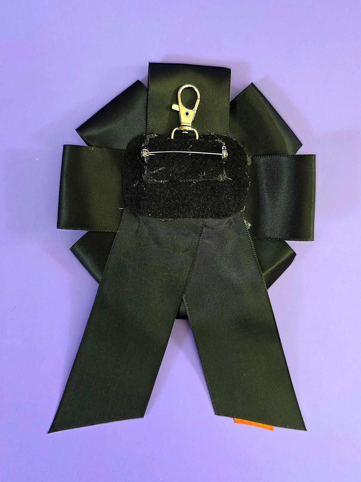 the back of the ribbon has a pin back and a keychain clip.