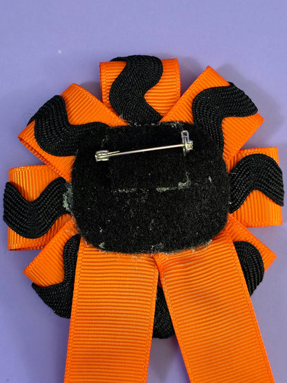 The back of the ribbon has a pin back attached to it.