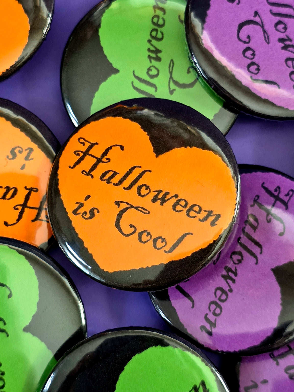 An orange button that says "Halloween is cool" with a black heart around it