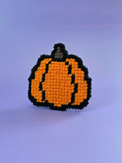 Small fluffy needlepoint pumpkin on a purple backdrop